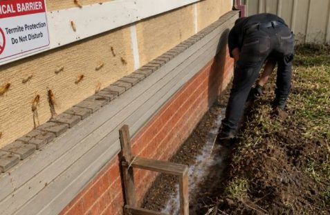 Technician installing a chemical barrier termites around a home foundation to prevent termite entry and protect the property from infestation.
